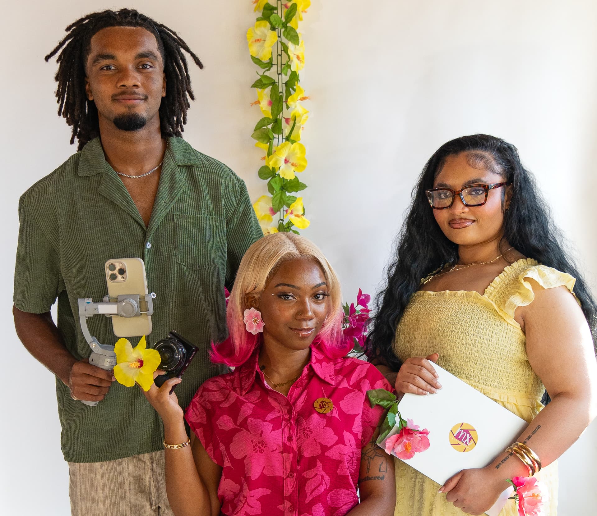 The three MilanX Productions creatives with camera, gimbal and laptop against a tropical backdrop